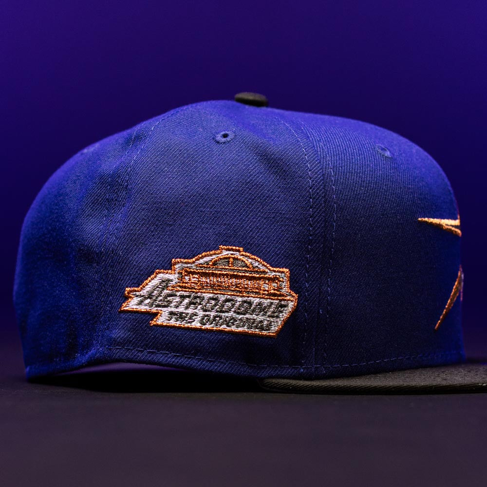 H Town North Houston Astros New Era Hat 5950 Fitted in blue with a black brim, featuring orange and white embroidered text and a side patch that reads “THE DOME THE ORIGINAL,” inspired by the OG Dark Royal Houston Astros style, shown against a purple background.