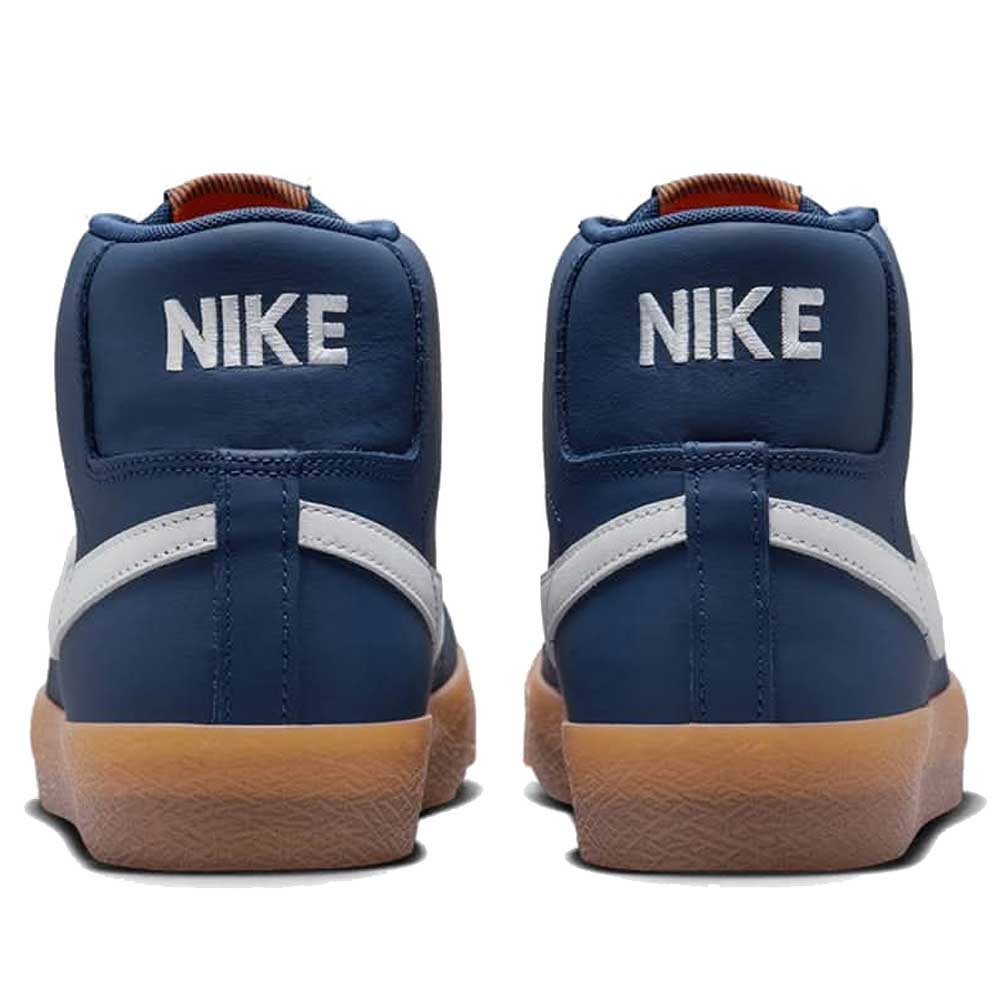 The Nike SB Blazer Mid FJ1680400 White Navy Leather Shoes are high-tops with white Nike heel branding, navy and white accents, and brown rubber soles—crafted for skateboarding with signature style.