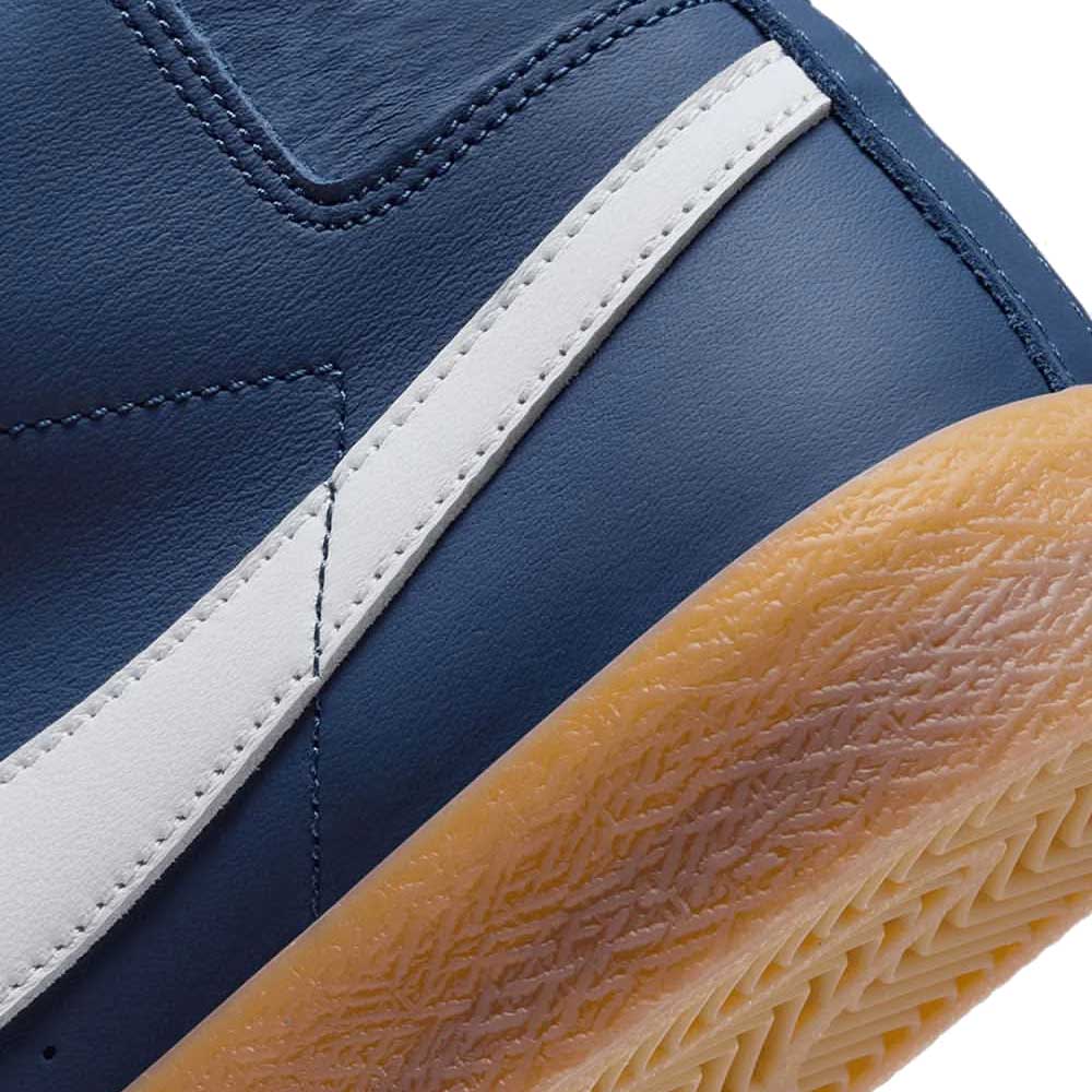 Close-up of Nike SB Blazer Mid FJ1680400 White Navy Leather Shoes featuring white and navy leather upper, white stripe detail, textured light brown sole, visible stitching, and Zoom Air cushioning for comfort.