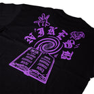 The Nike SB Purple Black Tee IR6747010 is a roomy fit, midweight cotton T-shirt featuring a purple open book graphic with swirling vortex, hand signs, stylized Nike SB text, and city names on the pages for durable daily comfort.