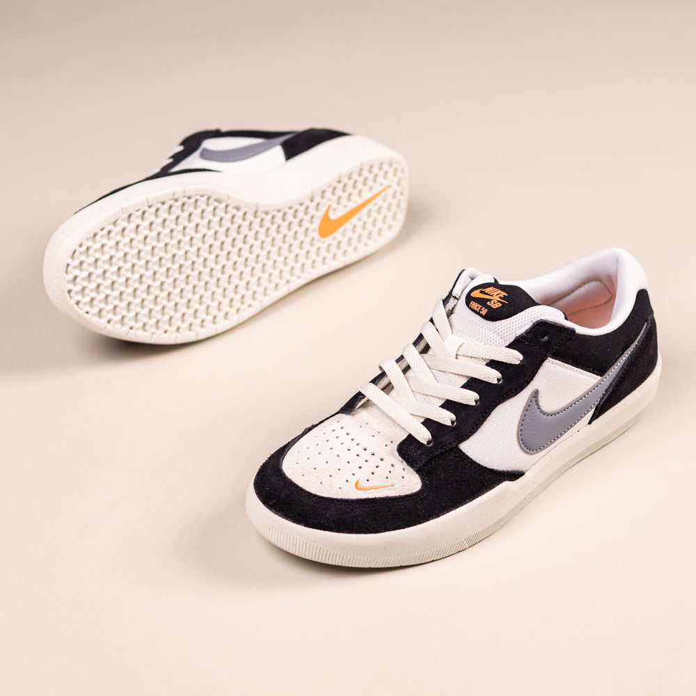 A pair of Black White DV5477012 Force 58 Nike SB Suede Skateboarding Shoes with black, white, and gray panels, orange details, and white soles. One shoe stands upright; the other is on its side, displaying the sole and orange Nike logo.