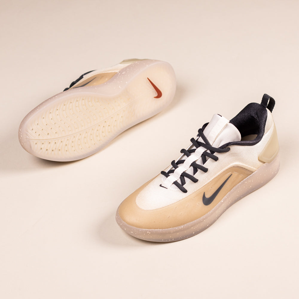 The FQ1273200 Khaki White Zoom Nyjah 4 Nike SB Skateboarding Shoes feature beige, white, and black colors with Nike swoosh logos, Air Zoom cushioning, and a red swoosh on the sole against a light background.