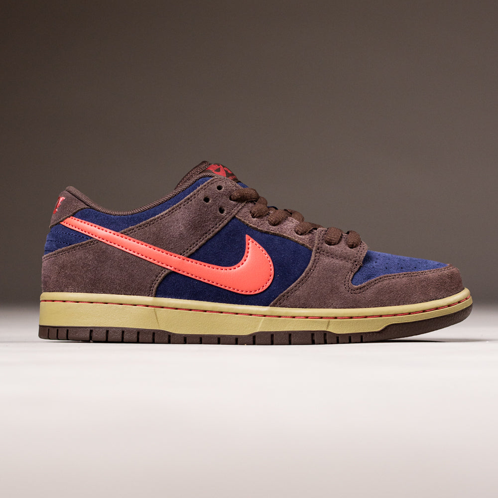 The Baroque Brown Adobe Midnight Navy Dunk Low Pro HQ1625200 Nike SB Suede Shoes feature a brown suede upper, navy panels, a bright orange Swoosh, and a beige sole, shown on a plain background.
