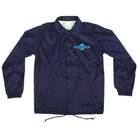 The OGBC Legacy Coach Windbreaker Longsleeve Jacket in navy blue features elastic cuffs, front pockets, and a small turquoise Independent logo—ideal for skateboarding and celebrating the Independent legacy.