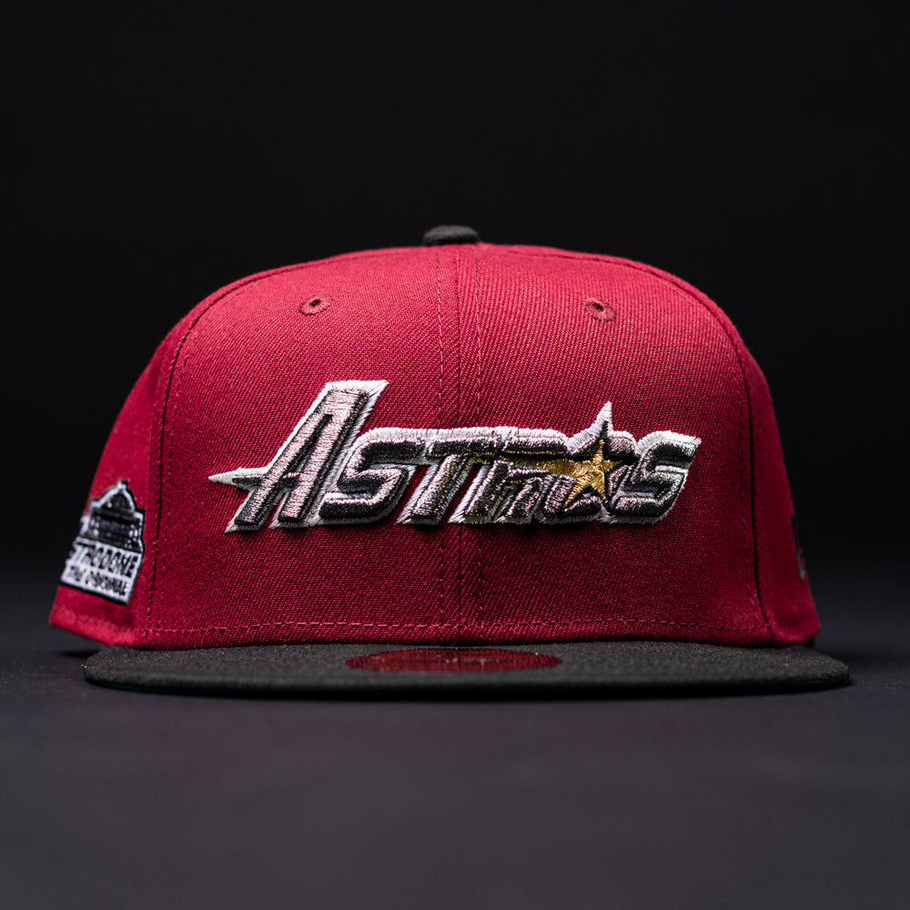 A Bloodline OG Cardinal Red Houston Astros New Era 5950 fitted hat, designed in red and black, featuring “Astros” embroidered in silver and gold on the front against a dark background.