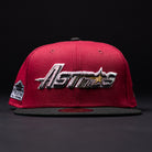 A Bloodline OG Cardinal Red Houston Astros New Era 5950 fitted hat, designed in red and black, featuring “Astros” embroidered in silver and gold on the front against a dark background.