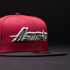 A Bloodline OG Cardinal Red Houston Astros New Era 5950 Fitted Hat in red and black, featuring “Astros” and a yellow star embroidered on the front, set against a dark background.