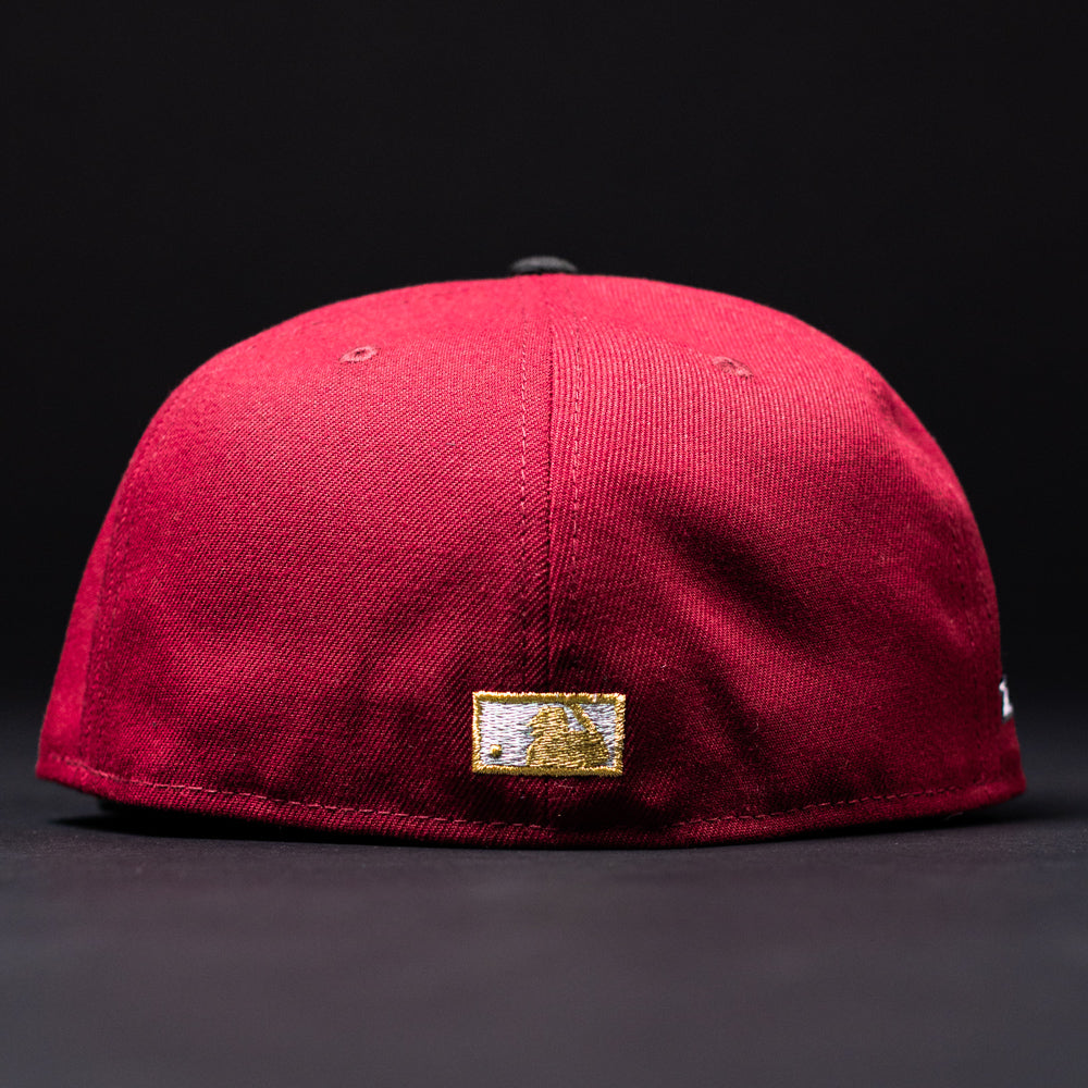 The Bloodline OG Cardinal Red Houston Astros New Era Hat 5950 Fitted is shown from the back against a black background, featuring a small embroidered gold and white patch near the bottom edge. This fitted cap by New Era blends subtle team pride with classic style.