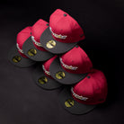 Six Bloodline OG Cardinal Red Houston Astros New Era Hat 5950 Fitted caps are stacked in two rows on a black surface. Each cap features a sticker on the brim and displays the Houston Astros logo embroidered on the front with bold Cardinal Red accents.