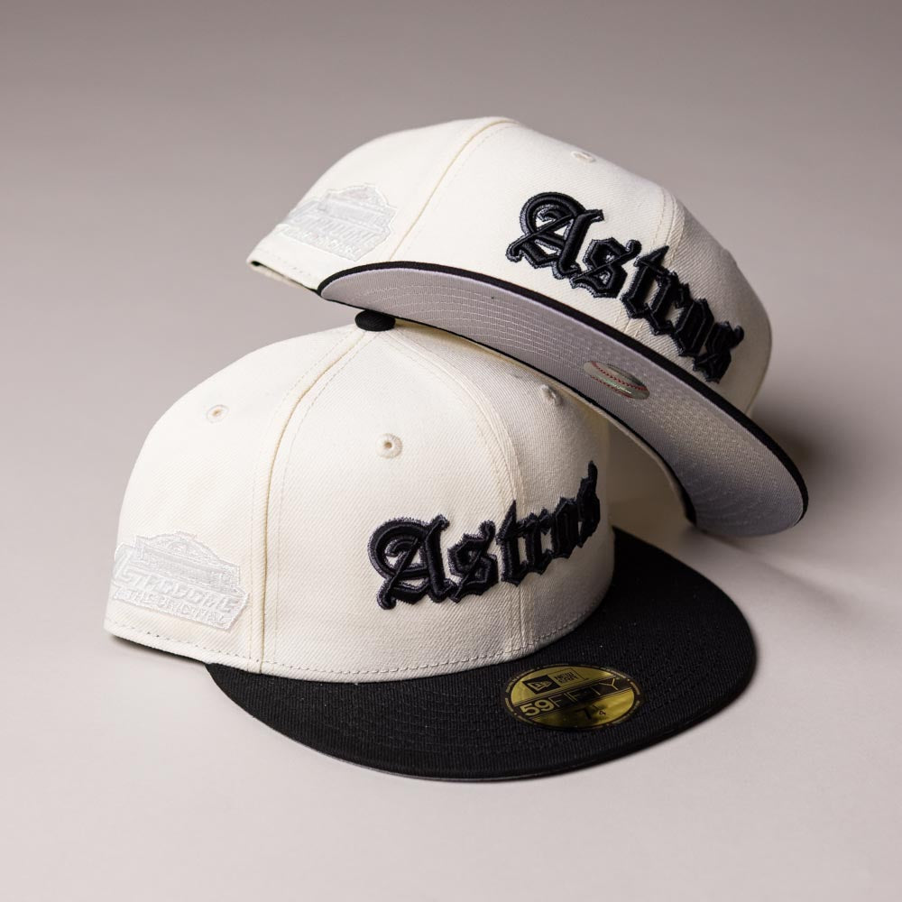 Two Straight Outta Southside OG Chrome Black Houston Astros New Era 5950 Fitted caps are stacked, featuring white panels with black brims. Each cap displays “Astros” in black gothic-style lettering on the front and a gray embroidered side patch. The iconic gold sticker is visible on one brim, highlighting this classic choice for Houston Astros fans.