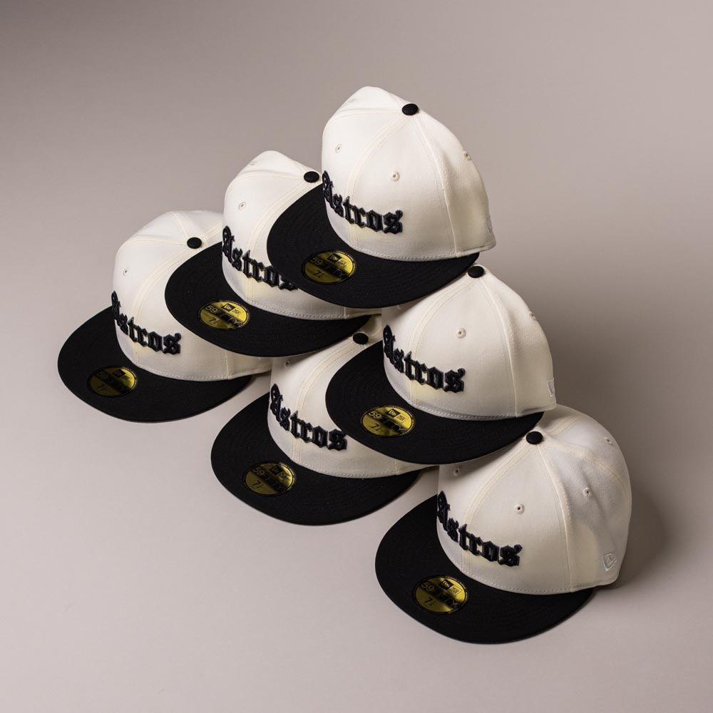 Five Straight Outta Southside OG Chrome Black Houston Astros New Era Hat 5950 Fitted caps are neatly stacked in a pyramid shape. These New Era hats feature cream and black colors with Astros in black script, shiny gold stickers on their visors, and are positioned on a plain light background.