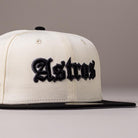 Showcasing classic Houston Astros pride, the Straight Outta Southside OG Chrome Black Houston Astros New Era Hat 5950 Fitted features a white crown with a black brim. The word “Astros” is embroidered in bold, black Gothic-style lettering on the front. This fitted cap is displayed against a plain, light-colored background.