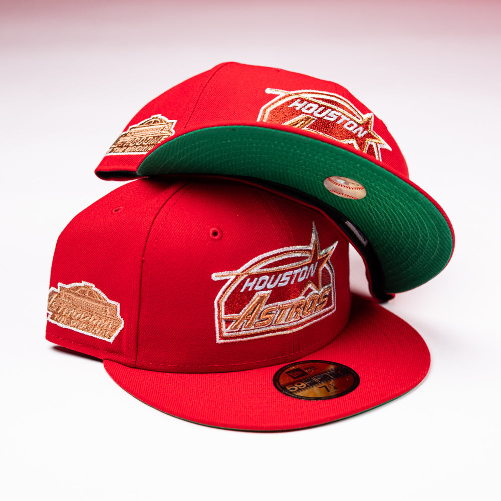 Two red H Town South Houston Astros New Era Hat 5950 Fitted caps with gold logos and stickers are displayed on a white surface, one cap resting atop the other to reveal the green underside of the brim.