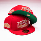 Two red H Town South Houston Astros New Era Hat 5950 Fitted caps with gold logos and stickers are displayed on a white surface, one cap resting atop the other to reveal the green underside of the brim.
