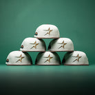 Six Copper Trails OG Walnut Egreen Houston Astros New Era 5950 Fitted hats are stacked in a pyramid shape against a green background.