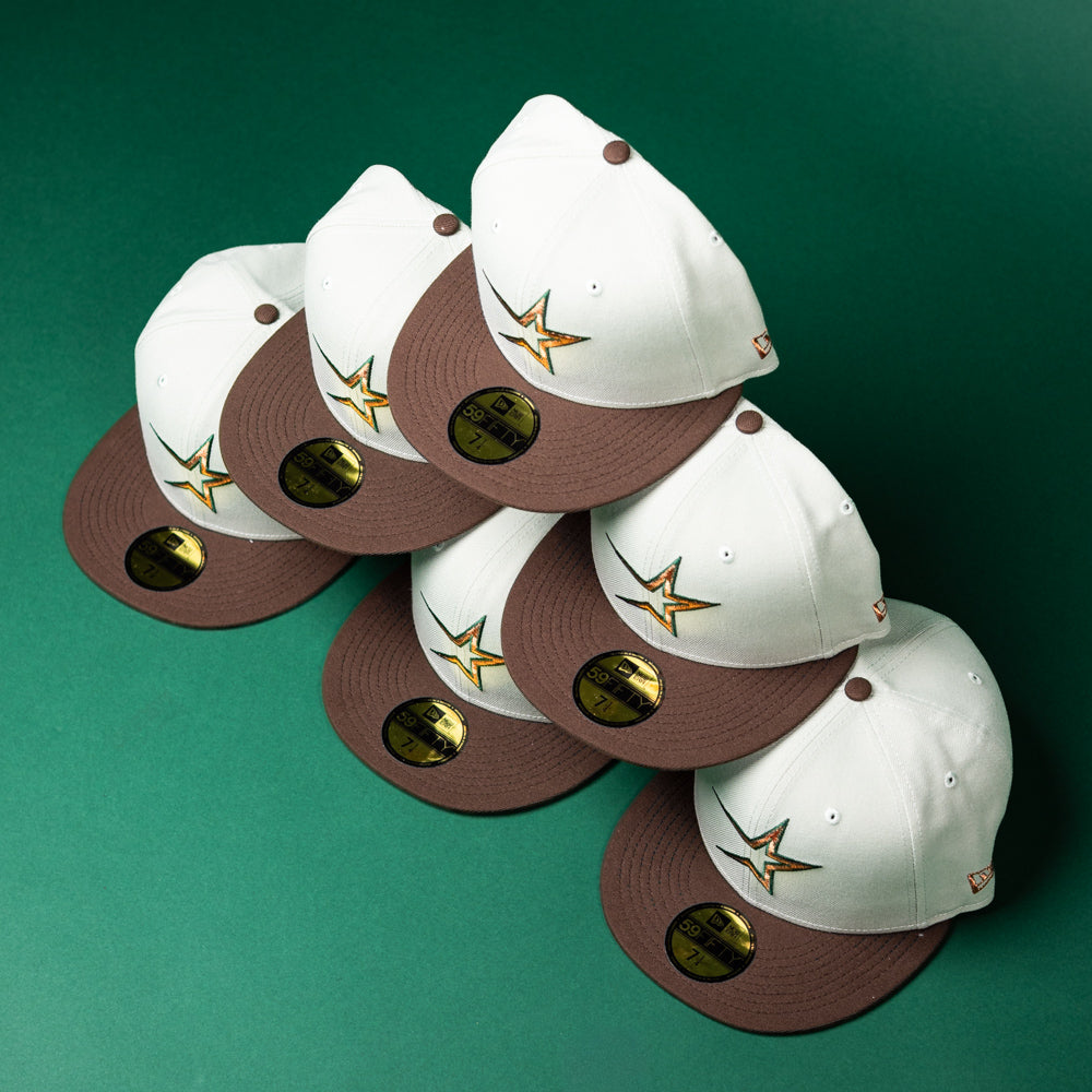 Six Copper Trails OG Walnut Egreen Houston Astros New Era 5950 fitted hats are arranged in a zigzag pattern on a green surface.