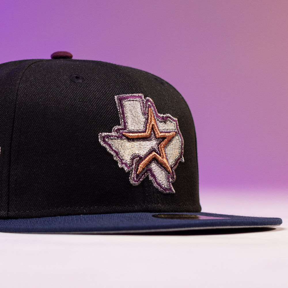 The Masterpiece WS05 Houston Astros New Era Hat 5950 Fitted is a black fitted cap with a flat brim, featuring an embroidered Texas outline and large star on the front, set against a purple gradient background.