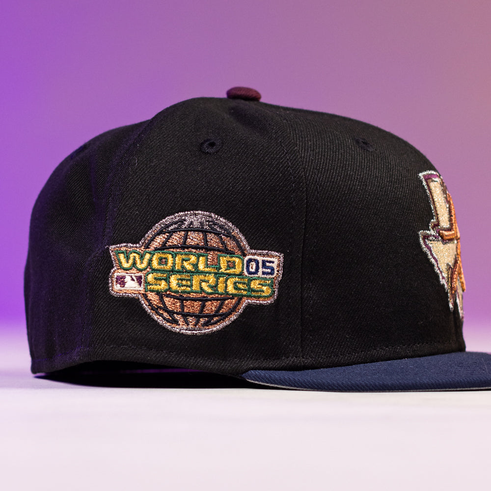 The Masterpiece WS05 Houston Astros New Era Hat 5950 Fitted is black with a World Series '05 patch on the side, shown on a purple gradient background. The front of the cap partially displays another logo.