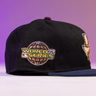 The Masterpiece WS05 Houston Astros New Era Hat 5950 Fitted is black with a World Series '05 patch on the side, shown on a purple gradient background. The front of the cap partially displays another logo.