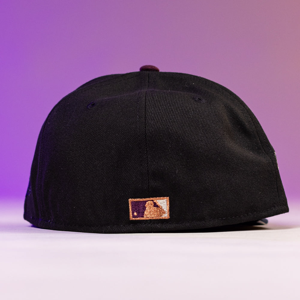 The Masterpiece WS05 Houston Astros 5950 Fitted New Era Hat is displayed from the back, showing a small MLB logo patch, set against a purple and pink gradient background.