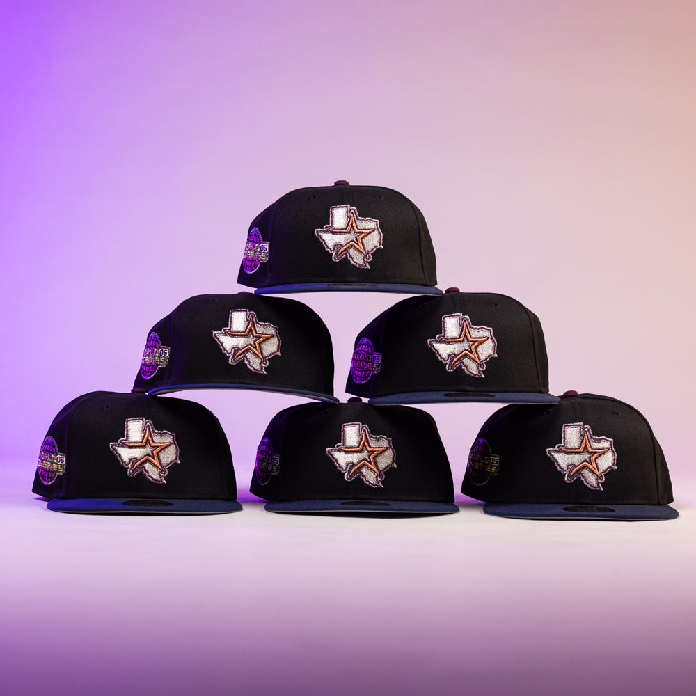 Six black Masterpiece WS05 Houston Astros New Era Hat 5950 Fitted caps are stacked in a pyramid, each sporting an outlined Texas with a star. The purple-to-beige gradient background is ideal for proud Astros fans.