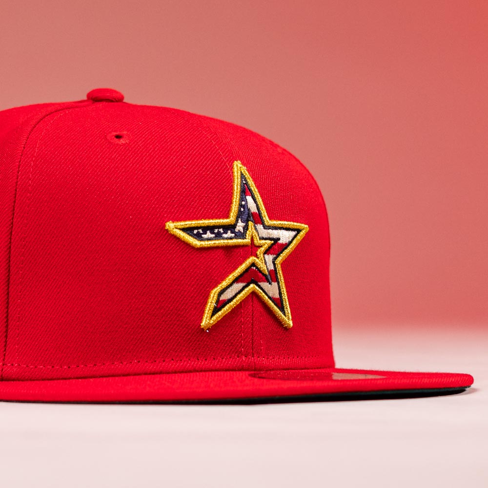The Crest Lo 2.0 Houston Astros New Era Hat 5950 Fitted is a red cap with a yellow-trimmed star logo on the front featuring an American flag pattern inside the star, shown on a matching red background.