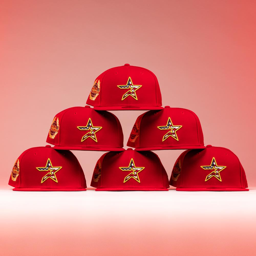 Six Crest Lo 2.0 Houston Astros New Era 5950 Fitted hats are arranged in a pyramid. Each has a yellow-bordered star patch on the front and a side Astros logo, displayed against a reddish-pink background with lighting.
