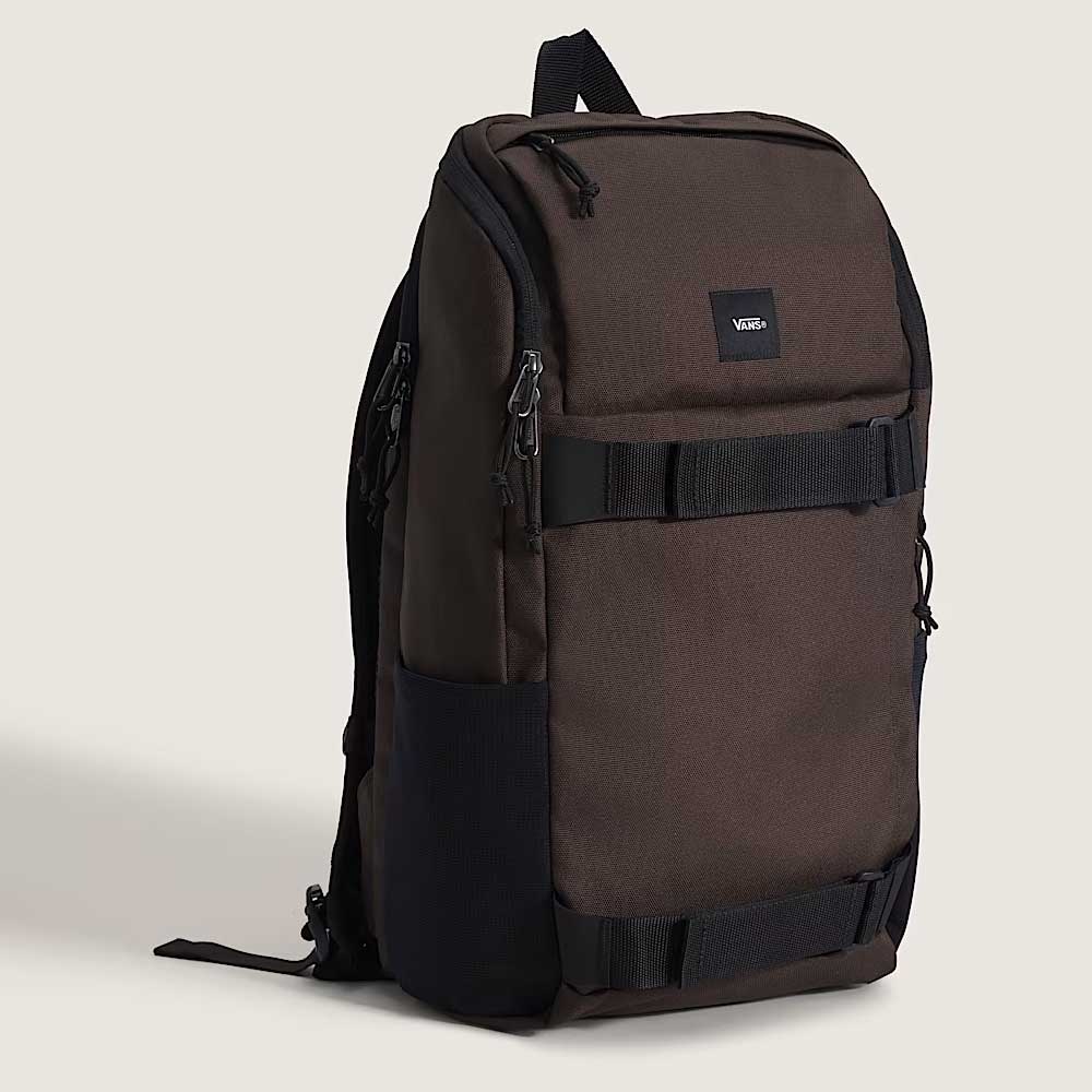 The Obstacle Skatepack Backpack (VN0A3I69OVB1) in brown ripstop by Vans Skateboarding features black straps, a front pocket, side mesh pockets, a small upper-front Vans logo patch, and a laptop compartment, shown upright on a plain light background.