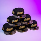 Six Oil Spill WS05 Houston Astros New Era Hat 5950 Fitted caps with black crowns and camo brims are stacked pyramid-style on a purple gradient background. Each features a gold Astros logo and commemorative side patch.