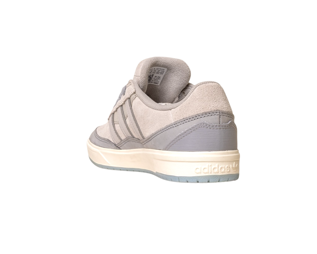 The JI0848 Granite White Tyshawn 2 Skateboarding Shoe by Adidas features leather and suede accents, highlighted from the back left to display the Adidas logo on the heel and its white and light gray rubber sole.