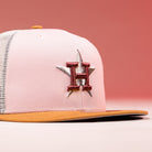 The Anglera 17WS Pink Trucker Houston Astros New Era Hat 5950 Fitted features a pink and white mesh design with a brown brim, embroidered star and H on the front, inspired by the Astros.
