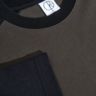 Close-up of the Polar Tee Doe Dirty Black Black, a color-blocked black and olive green cotton double jersey shirt with a black collar, white tag featuring an embroidered circular R logo, and visible stitching on the loose fit fabric.