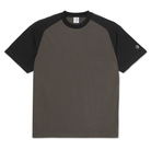 The Polar Tee Doe Dirty Black Black is a loose-fit, short-sleeved cotton double jersey T-shirt with a dark brown body, black raglan sleeves, a round black collar, and a small white embroidered logo on the left sleeve.