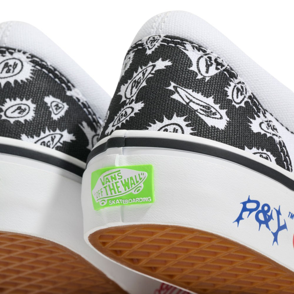 Close-up of two Punk and Yo x Vans Skate Slip On VN000EKPY281 Canvas Shoes, featuring black and white patterned canvas, a signature green Vans Off The Wall skateboarding logo on the heel, distinctive P&Y blue lettering on the white midsole above a gum outsole—part of the bold collaboration redefining skateboarding streetwear.