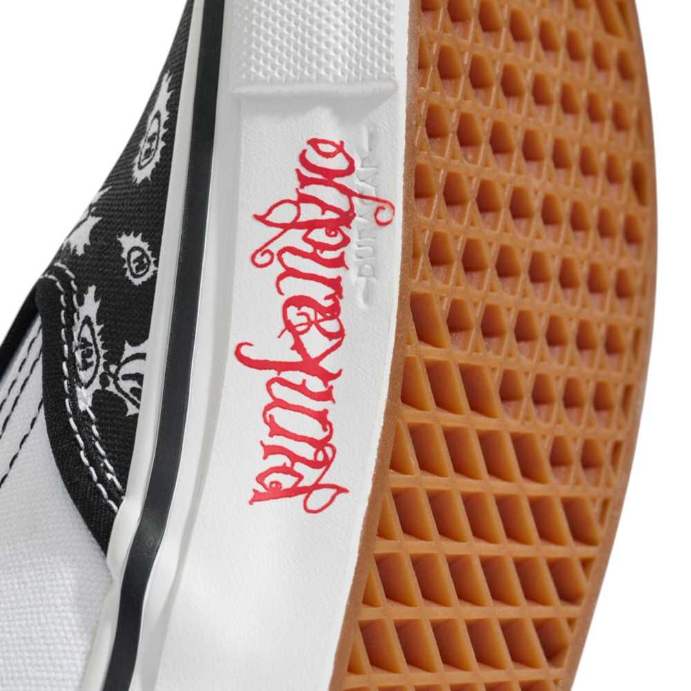 Close-up of the Punk and Yo x Vans Skate Slip On VN000EKPY281 Canvas Shoes, highlighting the sneaker’s waffle-patterned sole, “punkangelica” in red script along the side, and a portion of a black and white graphic on the upper—a tribute to skateboarding streetwear style.