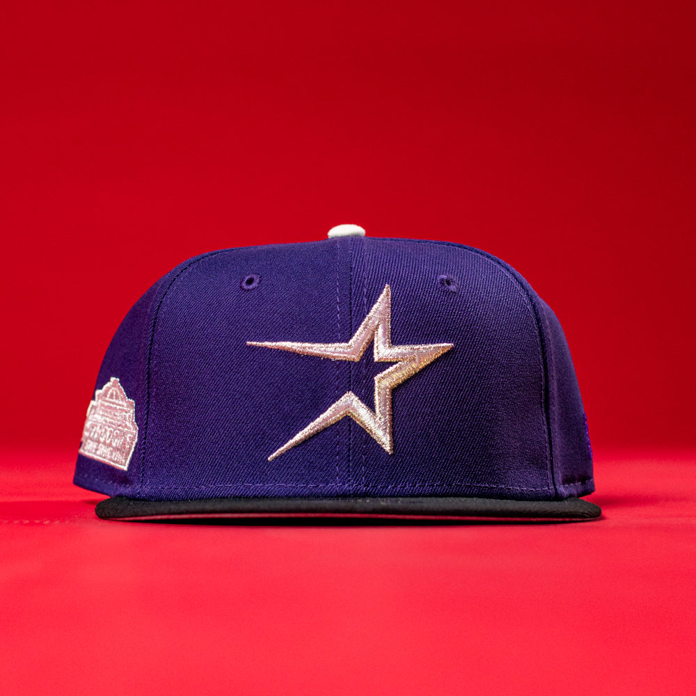 A purple De Uva Houston Astros New Era 5950 Fitted hat, featuring a large silver star logo on the front and a commemorative patch on the left side, is displayed against a solid red background.