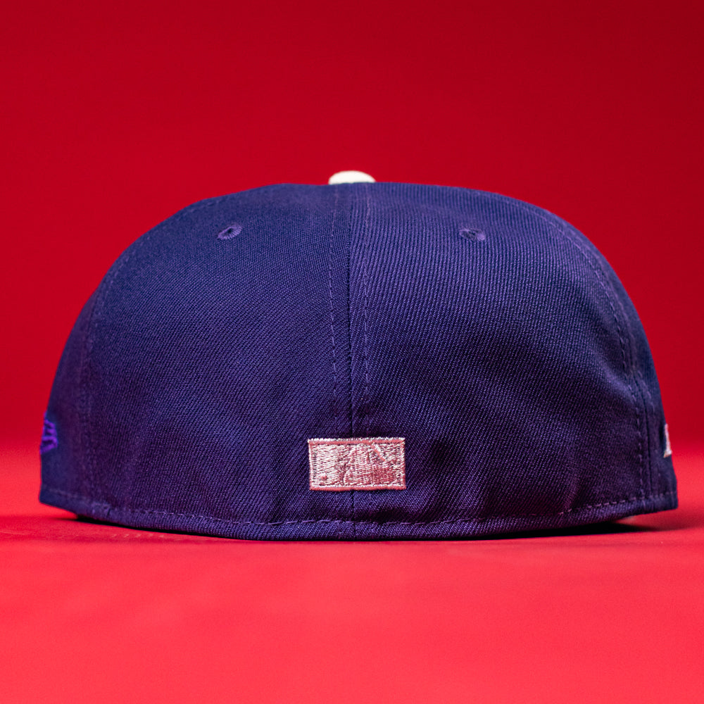 A De Uva New Era Purple Houston Astros 5950 Fitted cap is displayed from the back on a red surface, featuring a small metallic rectangular patch near the bottom center.