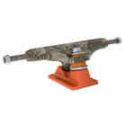 A set of Realtree APX INDY 144 Standard Stage 11 Trucks (set of two), featuring a camouflage-patterned hanger and an orange baseplate, is shown isolated on a white background.