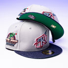 Two gray and blue New Era Unit 95 ASG Denim Houston Rockets 5950 fitted hats with embroidered sports logos, “All-Star Weekend Phoenix,” a basketball graphic, and patches. One is upright; the other is stacked to show its green underside.