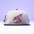 The Unit 95 ASG Denim Houston Rockets New Era Hat 5950 Fitted has a bold embroidered Rockets logo on the front and a vibrant NBA Finals patch on the side, shown against a purple background.