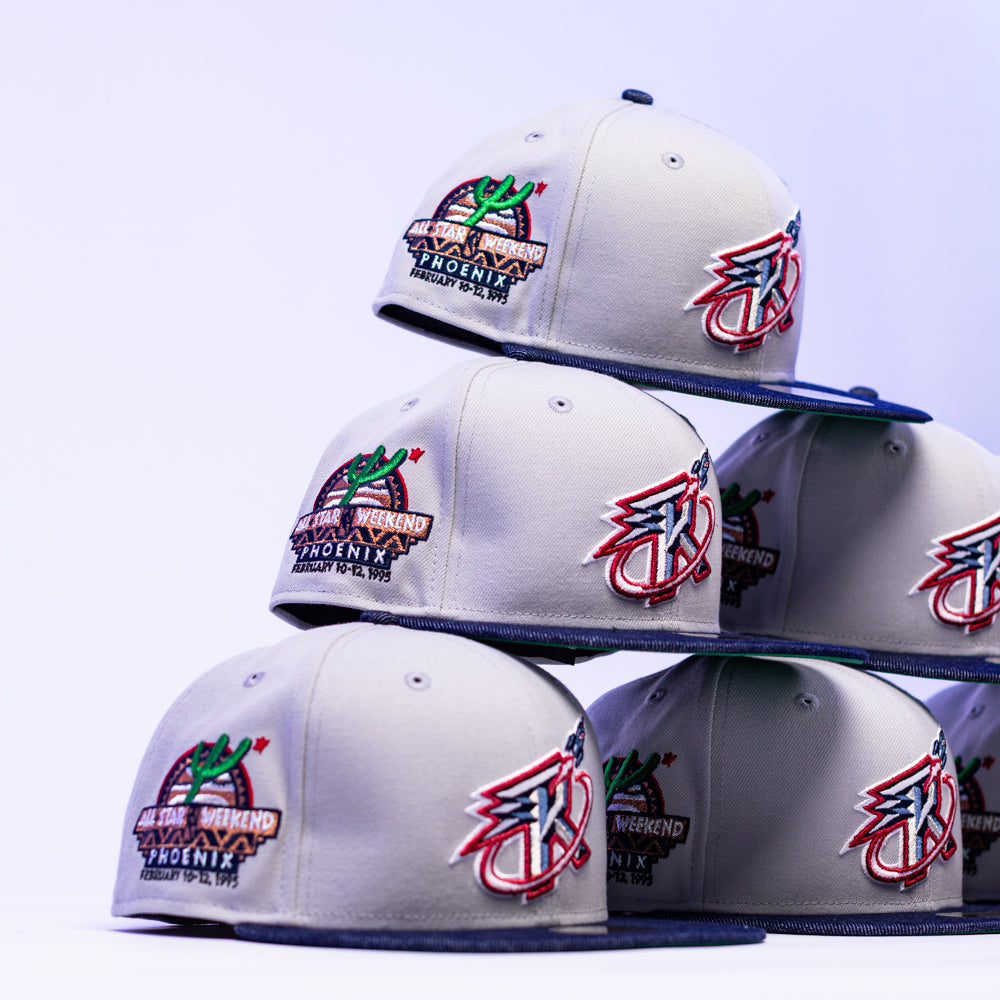 A stack of The Unit 95 ASG Denim Houston Rockets New Era Hat 5950 Fitted caps, embroidered with NBA All-Star Weekend Phoenix, February 10-12, 1995 and a colorful logo, displayed on a light purple background.