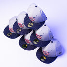 Six gray and navy blue The Unit 95 ASG Denim Houston Rockets New Era Hat 5950 Fitted caps, each with a red, white, and blue patch on the front and gold stickers on the brim, are stacked in a zigzag pattern on a white surface.