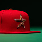 Introducing the Rusty Screw OG Scarlet Copper Houston Astros New Era Hat 5950 Fitted—a striking red fitted cap with a prominent embroidered gold and black star logo on the front, perfectly embodying classic Astros style against a dark green and black backdrop.