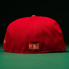 A Rusty Screw OG Scarlet Copper Houston Astros 59FIFTY Fitted hat by New Era is displayed from the back against a dark green background, showcasing the MLB logo patch near the bottom edge—an iconic design for Astros fans of all ages.