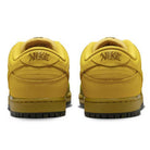 Back view of the Saffron Quartz Pear Hatch Chili Dunk Low Pro IO0427300 Nike SB Skateboarding Shoes, yellow low-tops with black soles and bold embroidered tiger graphics on the heels, reminiscent of the classic Dunk Low style.