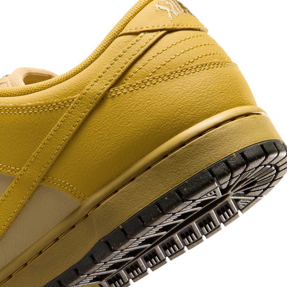Close-up of the heel and sole of the Saffron Quartz Pear Hatch Chili Dunk Low Pro IO0427300 Nike SB Skateboarding Shoe, featuring yellow textured leather with stitched details and a partial view of the black and yellow rubber outsole.