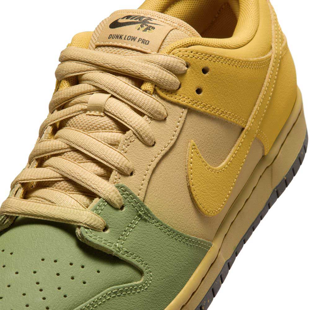 Close-up of the Saffron Quartz Pear Hatch Chili Dunk Low Pro IO0427300 Nike SB Skateboarding Shoe, featuring light yellow laces, a yellow tongue and side panel, and a green toe box. The iconic Nike Dunk logo appears on both the tongue and side.