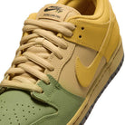 Close-up of the Saffron Quartz Pear Hatch Chili Dunk Low Pro IO0427300 Nike SB Skateboarding Shoe, featuring light yellow laces, a yellow tongue and side panel, and a green toe box. The iconic Nike Dunk logo appears on both the tongue and side.