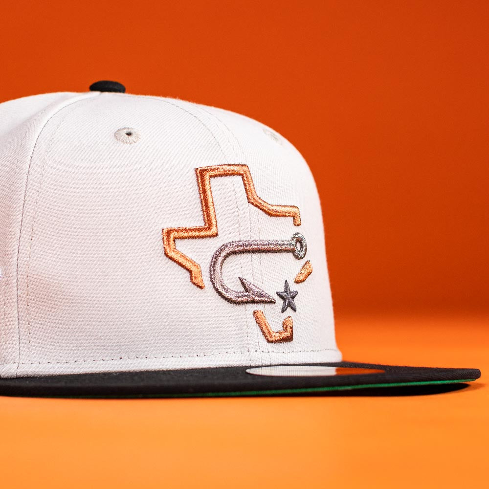 The Backlash Corpus Christi Hooks New Era 5950 Fitted Hat features a silver, black, and white design with an embroidered Texas outline, fishing hook, and star—resembling the iconic team cap—set against an orange background.