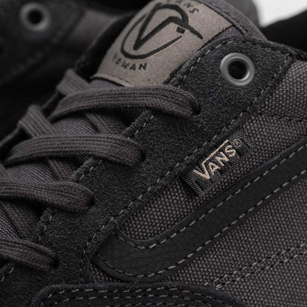 Close-up of the black Suede Rowan Vans Shoes (Skate Rowan Asphalt White VN0A5JICRP9), showing fabric texture, stitching, lace holes, and two Vans logos—one on the tongue and one on the side. Inspired by pro skater Rowan Zorilla.